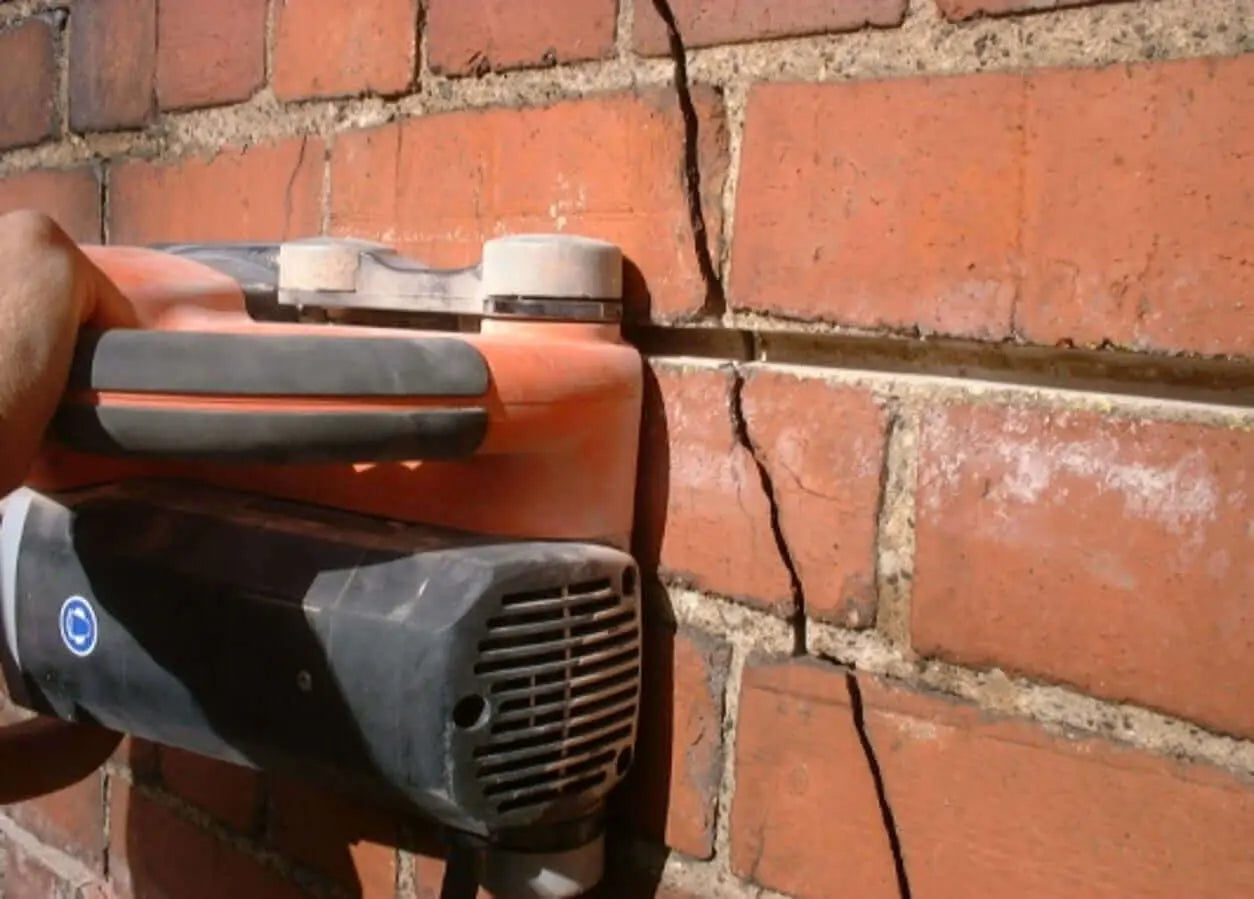 A wall chaser raking out a mortar joint for crack stitch repairs