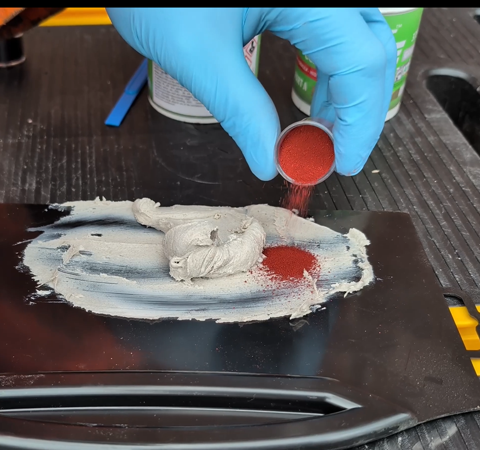 Colour powder paint being poured onto the mixed resin ready to use as a brick filler